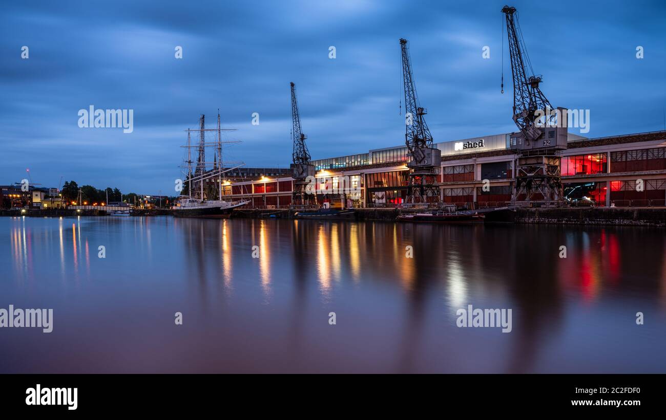 Bristol, England, Großbritannien - 8. Juni 2020: Das M Shed Museum wird in der Dämmerung beleuchtet, entlang der historischen festgetäuten Boote und Hafenkrane auf Bristol's regenerierten Post-i Stockfoto