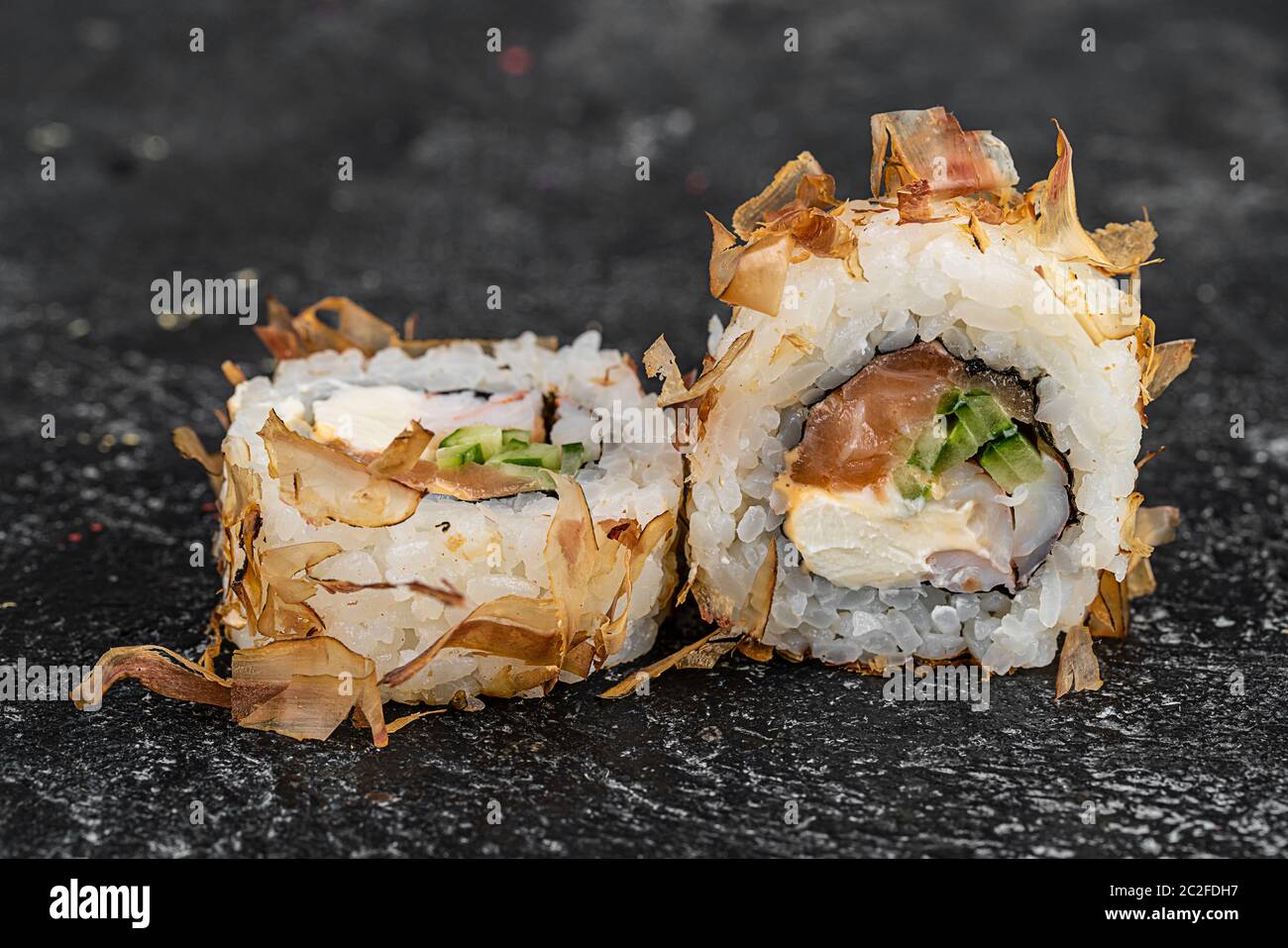 Sushi-Rolle mit Lachs, Käse, Gurken und Aal Rasur isoliert auf einem schwarzen Hintergrund mit Reflexion Stockfoto