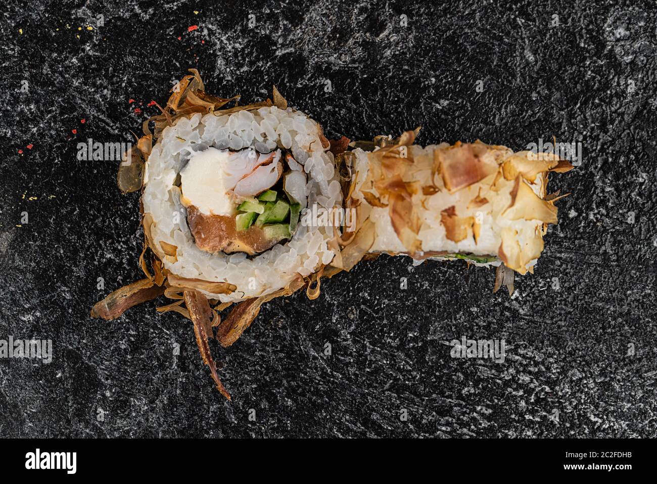 Sushi-Rolle mit Lachs, Käse, Gurken und Aal Rasur isoliert auf einem schwarzen Hintergrund mit Reflexion Stockfoto