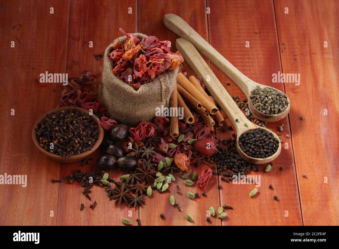 Getrocknete Gewürze: Schwarzer Pfeffer, grüner Pfeffer, Mace oder Javiithri Blume, Muskatnuss, Nelke, Zimt, Kardamom, Sternanis auf einer hölzernen Oberfläche angeordnet Stockfoto