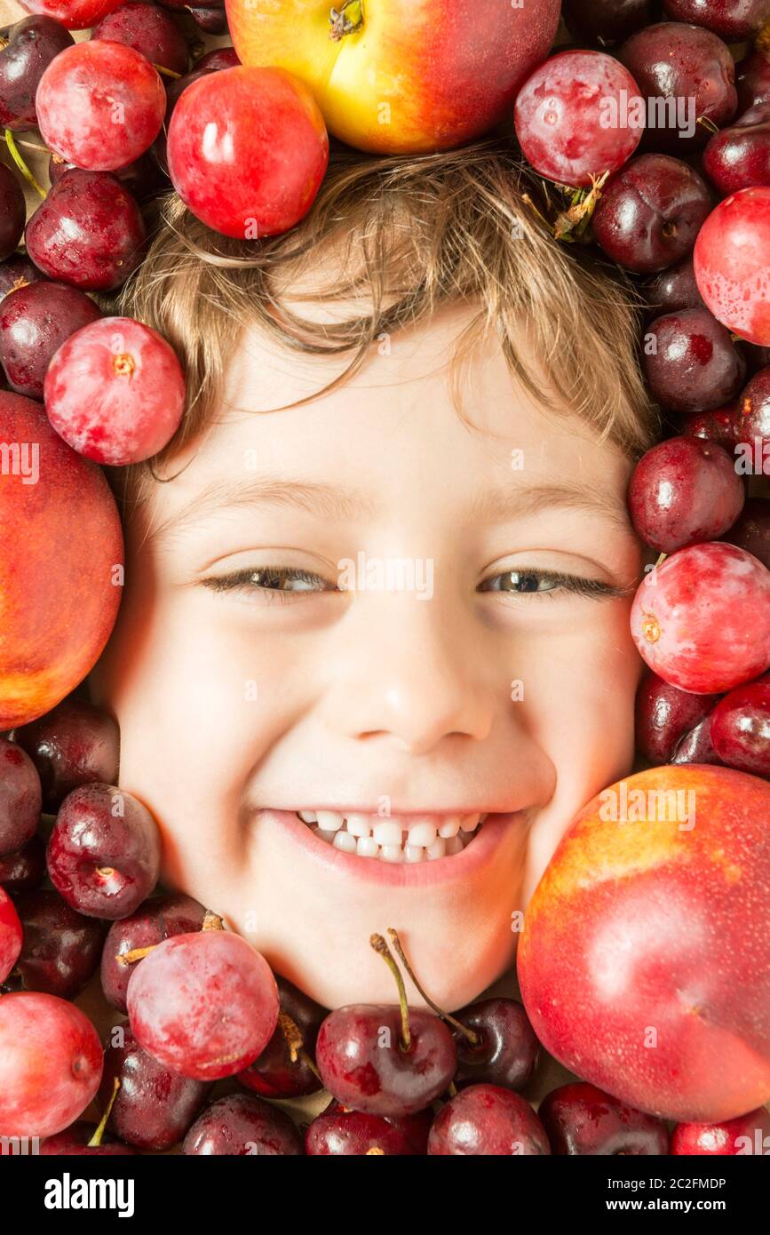 Kreatives Porträt eines Jungen mit seinem Gesicht umgeben von Früchten. Stockfoto