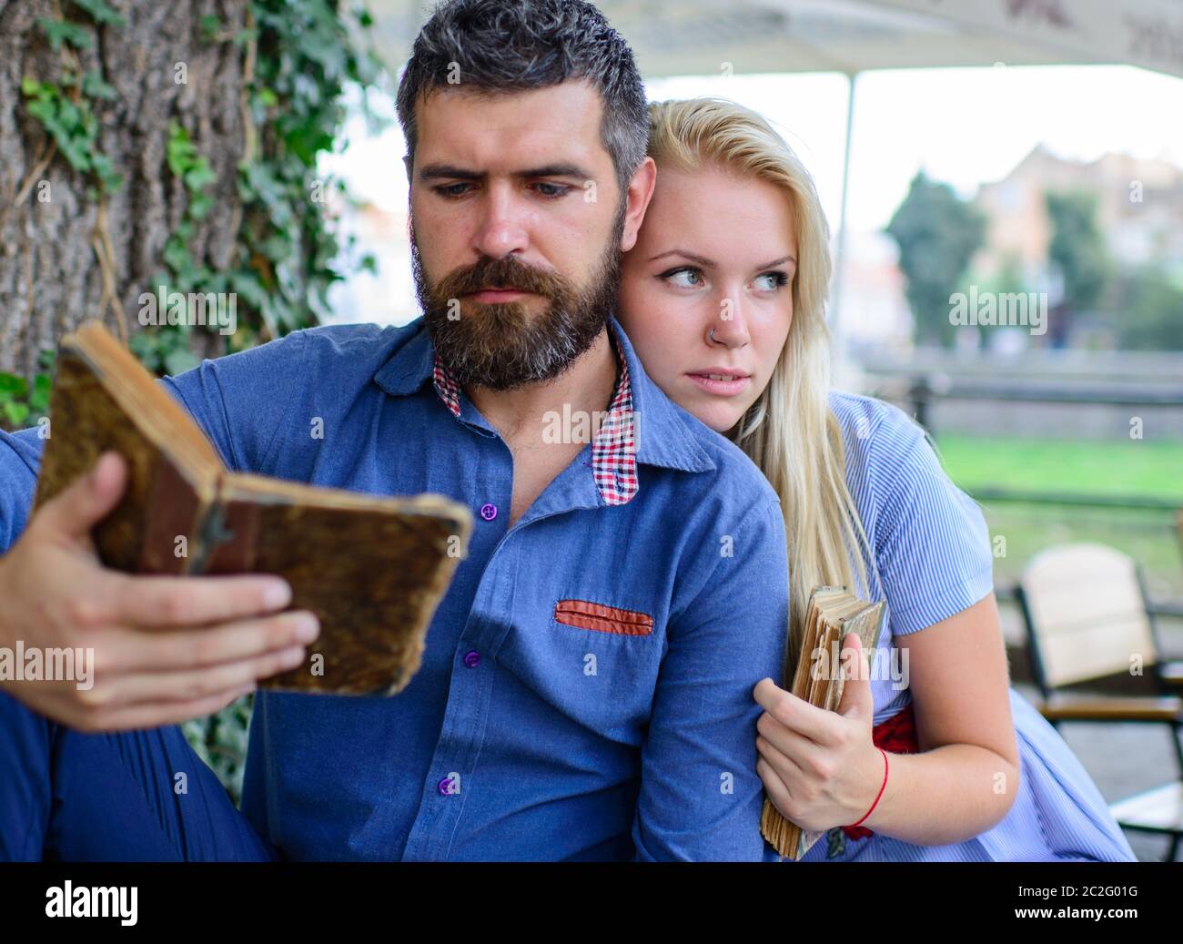 Schönes liebevolles Paar, das im Sommerpark sitzt und ein Buch liest. Liebe und Zärtlichkeit. Beziehungen, Freundschaften, Bildung, Lifestyle-Konzept Stockfoto