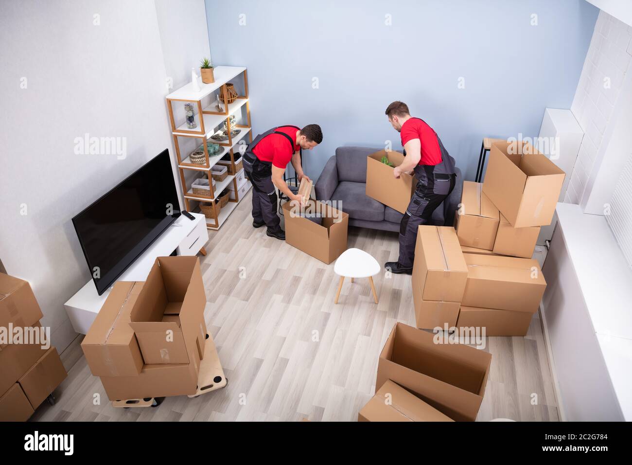 Zwei junge Movers in Uniform Kommissionierung und das Inverkehrbringen von Produkten in der Kartons Stockfoto