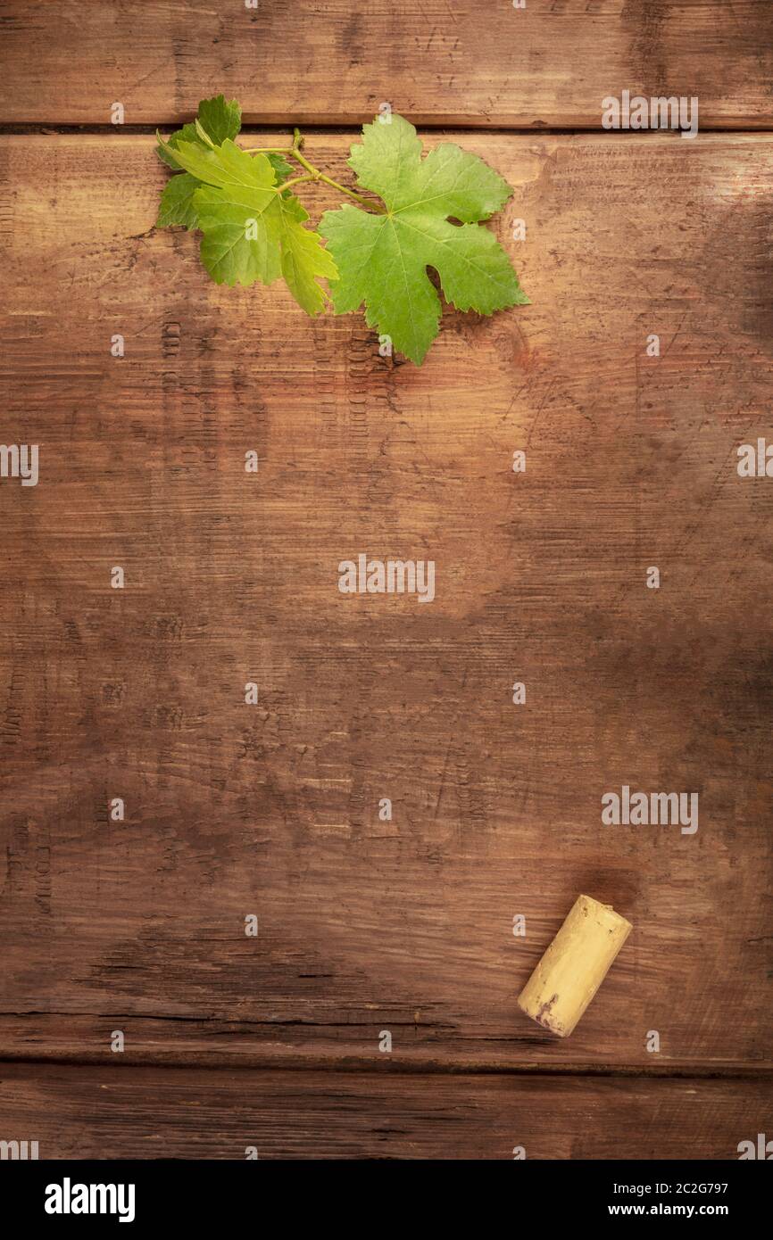 Eine Designvorlage für ein Weinmenü oder eine Weinverkostung Einladung. Ein Weinblatt und ein Weinkorken, von oben auf einem dunklen rustikalen Holz geschossen Stockfoto