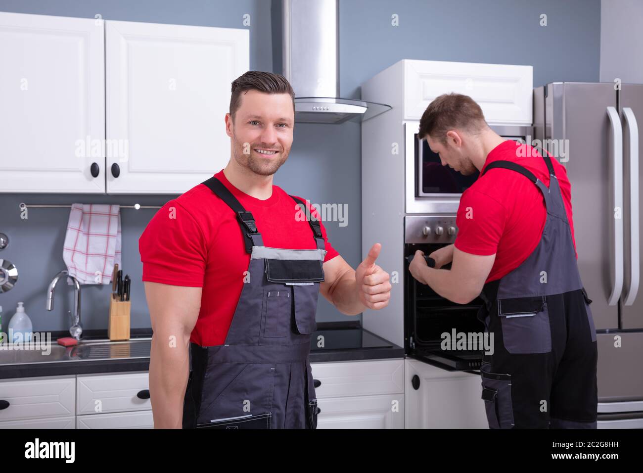 Techniker mit Daumen nach oben Zeichen Vor seinem Assistenten der Instandsetzung der Ofen in der Küche Stockfoto