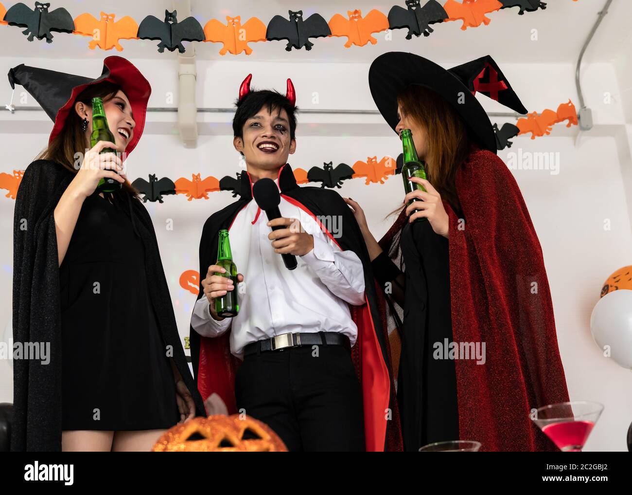 Gruppe für junge Erwachsene und jugendliche Menschen feiern eine Halloween  Party Karneval in Halloween Kostüme Alkohol Bier singen ein Lied ein  Stockfotografie - Alamy