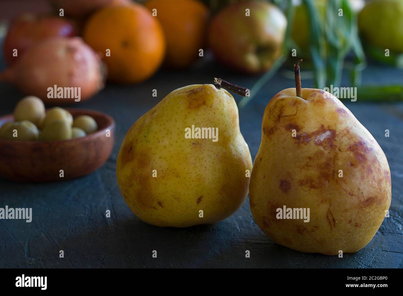 Einige Birnen und andere Früchte auf einem dunklen Tisch Stockfoto