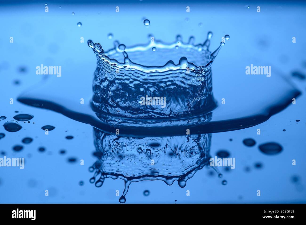 Wasser spritzt auf Glas auf einem blauen Hintergrund Tropfen Wasser Stockfoto