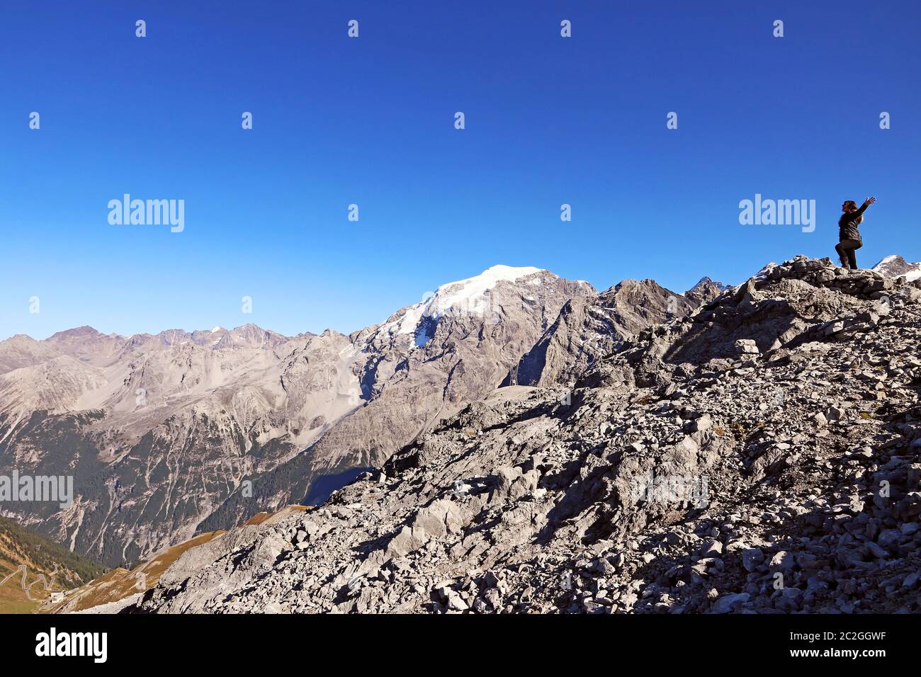 Eine Frau in den Bergen streckt ihre Arme vor Freude aus. Spaß beim Bergsteigen Stockfoto