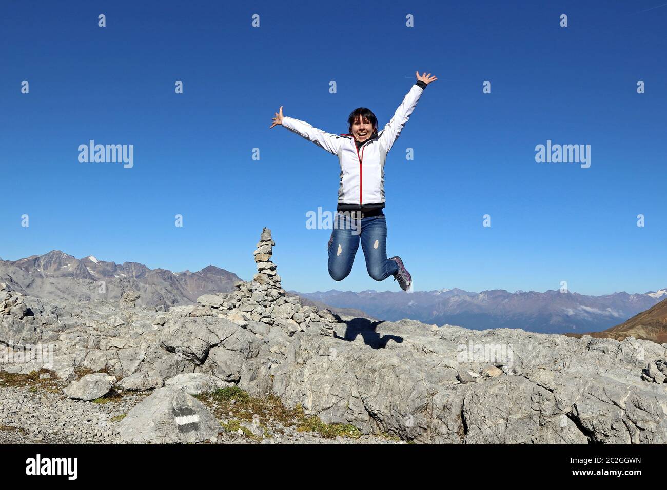 Eine junge Frau springt in die Luft in den Bergen und lacht vor Freude. Stockfoto