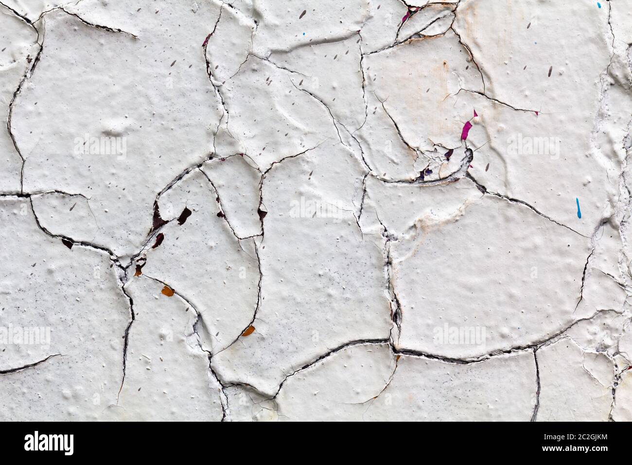 Oberflächenstruktur mit weißer Farbe und Rissen an Betonwand. Für abstrakte Hintergründe. Deutschland Stockfoto