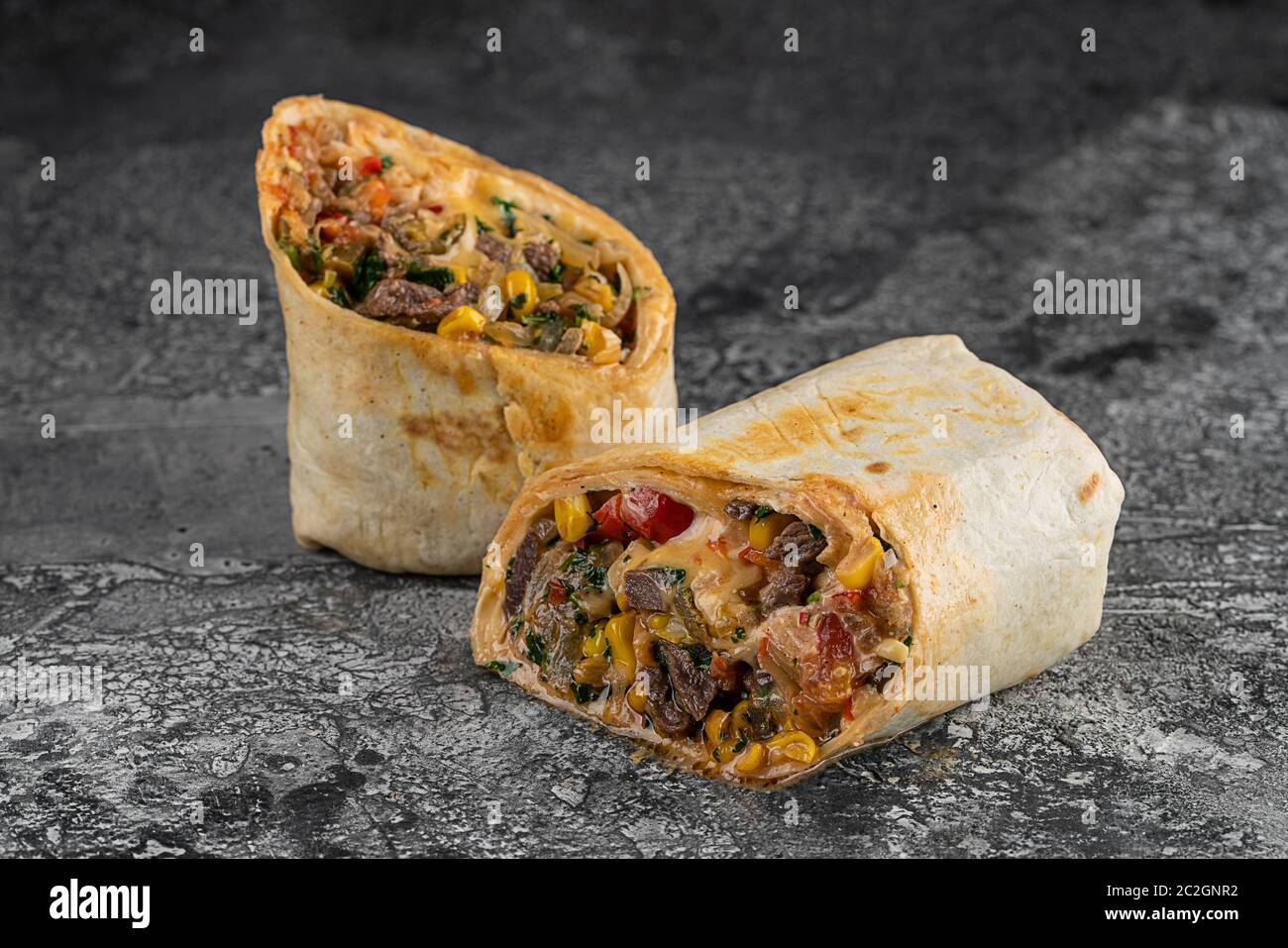 Burrito und Shawarma Wraps mit Rindfleisch und Schweinefleisch Gemüse auf Holztisch auf schwarzem Hintergrund Stockfoto