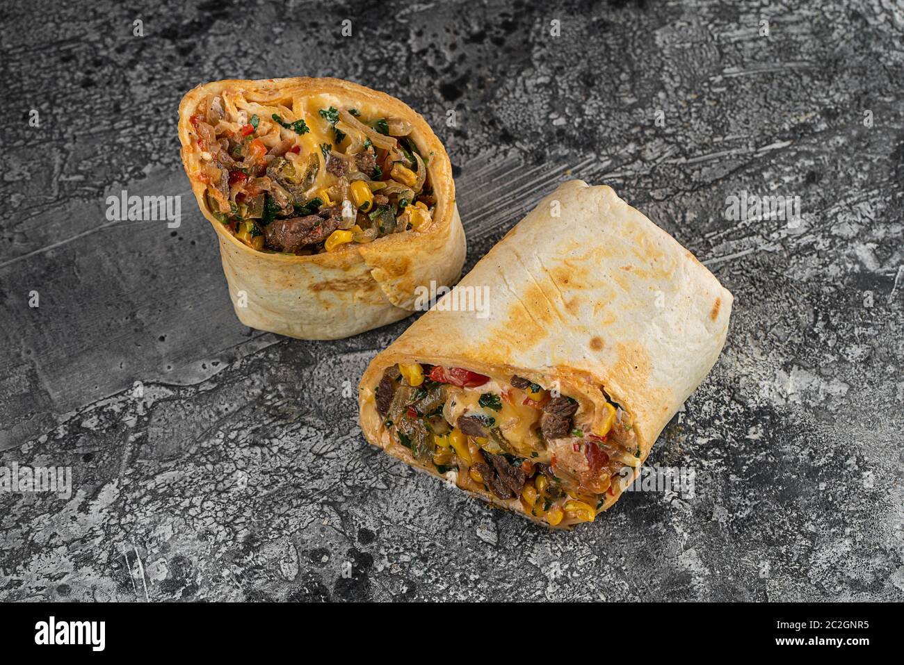 Burrito und Shawarma Wraps mit Rindfleisch und Schweinefleisch Gemüse auf Holztisch auf schwarzem Hintergrund Stockfoto