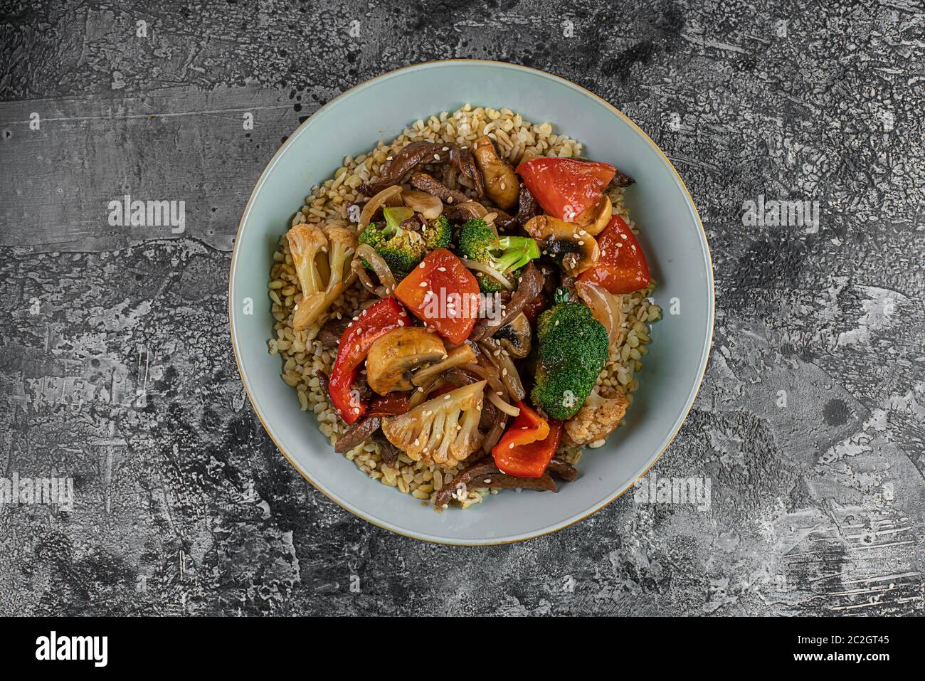 Bulgur Pilaf mit Fleisch und Gemüse. Köstliches warmes Mittagessen auf schwarzem Hintergrund. Östliche Küche. Draufsicht, oben, flach Stockfoto