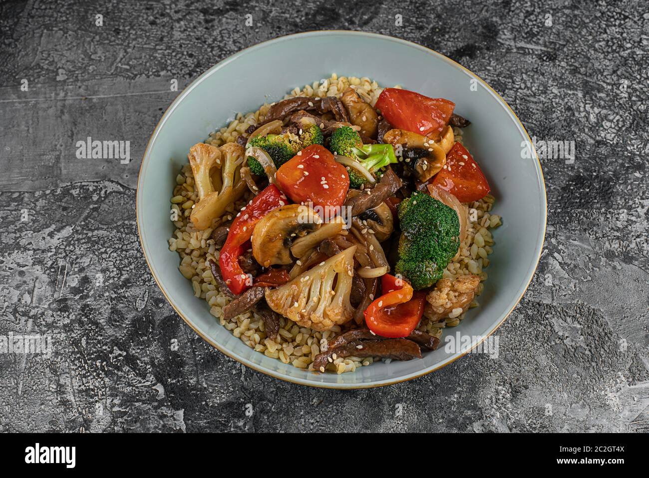 Bulgur Pilaf mit Fleisch und Gemüse. Köstliches warmes Mittagessen auf schwarzem Hintergrund. Östliche Küche. Draufsicht, oben, flach Stockfoto