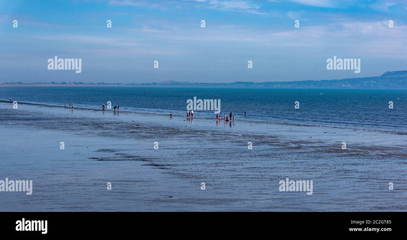 Am Rande des Wassers am Dollymount Strand in Dublin, Irland, versammelten sich Menschen. Stockfoto