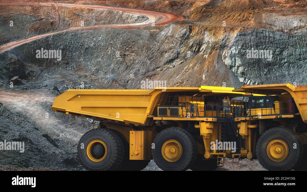 In der Goldmine ein großer gelber Lastwagen, der Golderz zur Bearbeitungsmaschine transportiert, Panoramaansicht Stockfoto