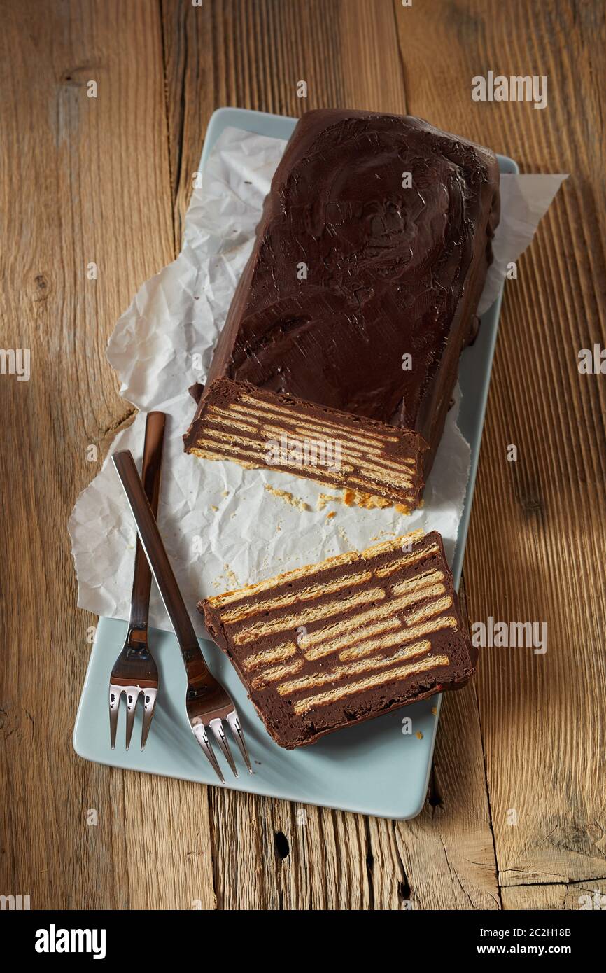 Laib-förmige Kalter Hund Kuchen mit einem Stück geschnitten, weiche Kekse. Auf blau Keramik Fach mit ein paar Gabeln serviert. Von abo Gesehen Stockfoto