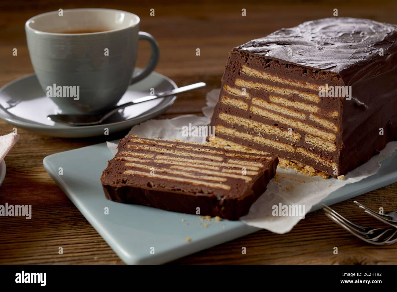 Brauner butter Keks Kuchen mit Schokoladenglasur, serviert mit Kaffee auf blau Keramik fach Nahaufnahme auf hölzernen Tisch Stockfoto