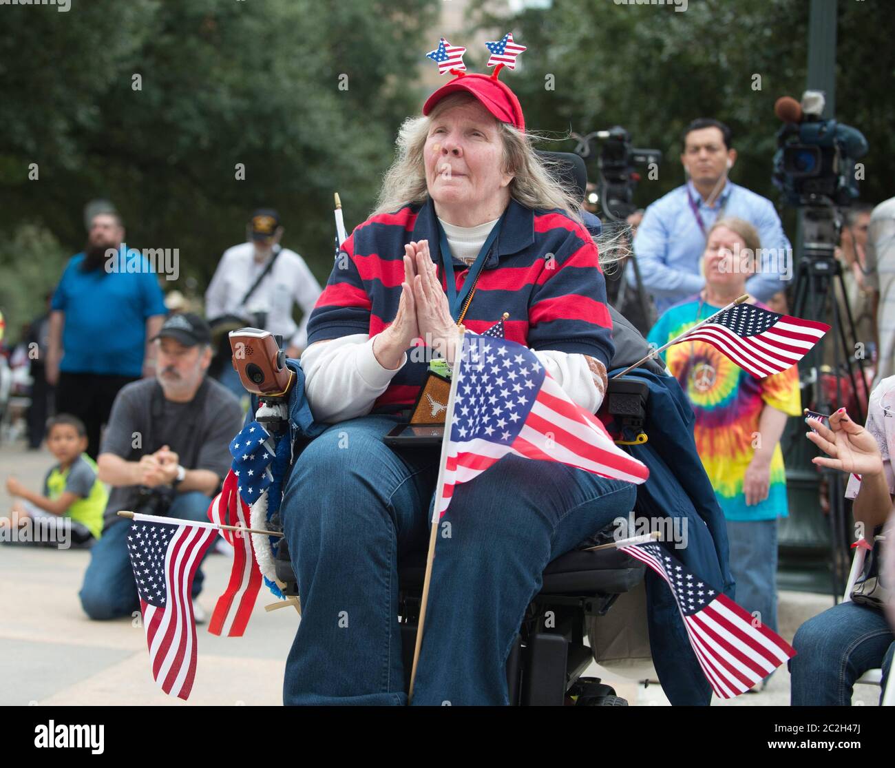 Austin Texas, USA, November 11 2015: Jean Crawford aus Austin, der in einem Rollstuhl mit Flaggen sitzt, applaudiert den Rednern während der jährlichen Veterans Day Zeremonie im Texas Capitol. ©Bob Daemmrich Stockfoto