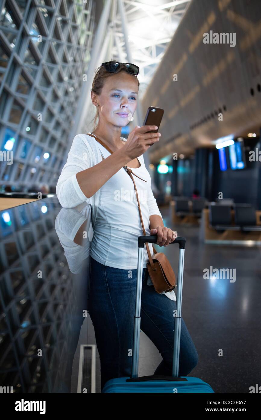 Junge Frau mit ihrem Gepäck an einem internationalen Flughafen und warten auf Ihren Flug in der Lounge Zone, nachdem man durch die Sicherheitskontrolle Verfahren Stockfoto
