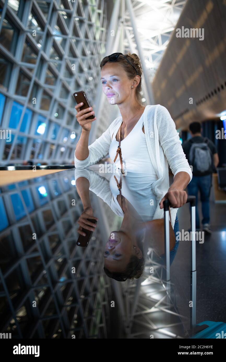 Junge Frau mit ihrem Gepäck an einem internationalen Flughafen und warten auf Ihren Flug in der Lounge Zone, nachdem man durch die Sicherheitskontrolle Verfahren Stockfoto