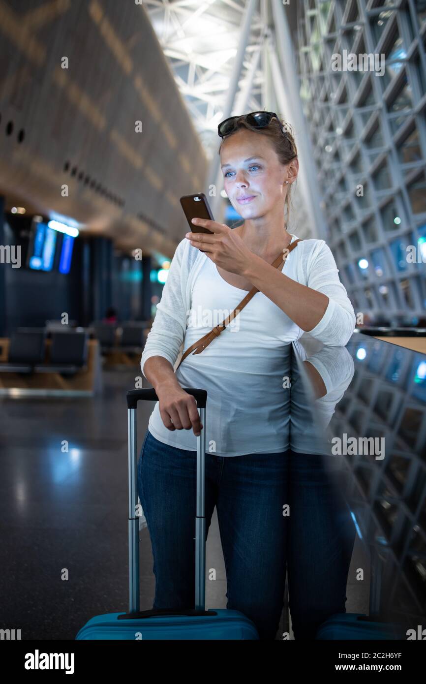 Junge Frau mit ihrem Gepäck an einem internationalen Flughafen und warten auf Ihren Flug in der Lounge Zone, nachdem man durch die Sicherheitskontrolle Verfahren Stockfoto