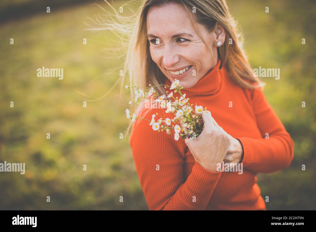 Portrait einer hübschen Frau mittleren Alters in einem Park, Blumen pflücken, im Freien genießen Stockfoto