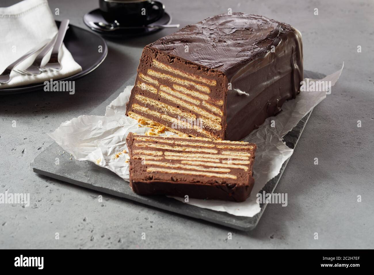 Bar-förmigen Schokoladenkuchen mit Gebäck 2-in-1-innen und Schokoladenglasur. Ungekocht dessert Kalter Hund oder Igel Slice. Auf weissem Papier auf g serviert. Stockfoto