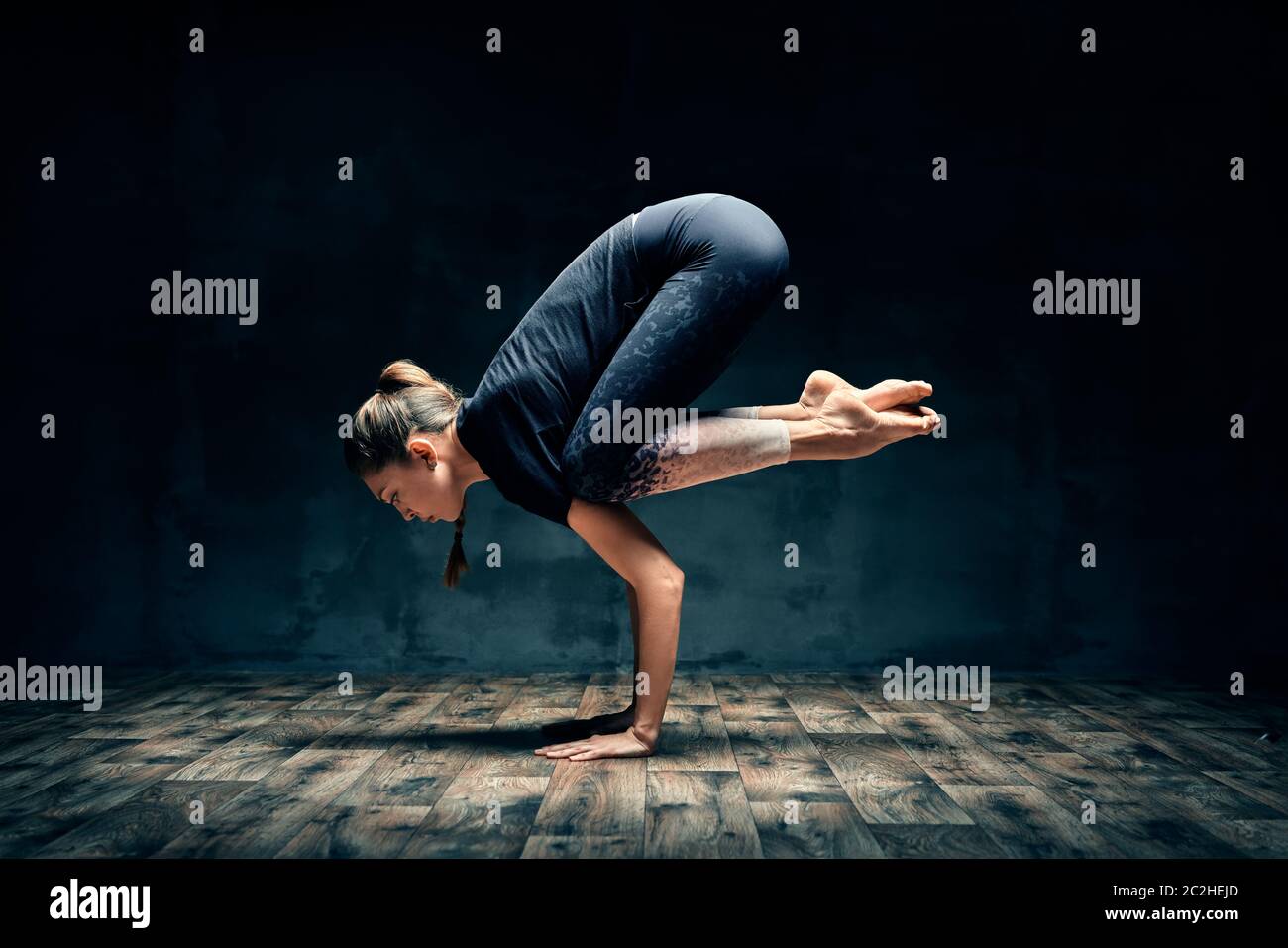 Junge Frau praktiziert Yoga tun Unterarm stehen Kran stellen Asana in dunklen Raum Stockfoto