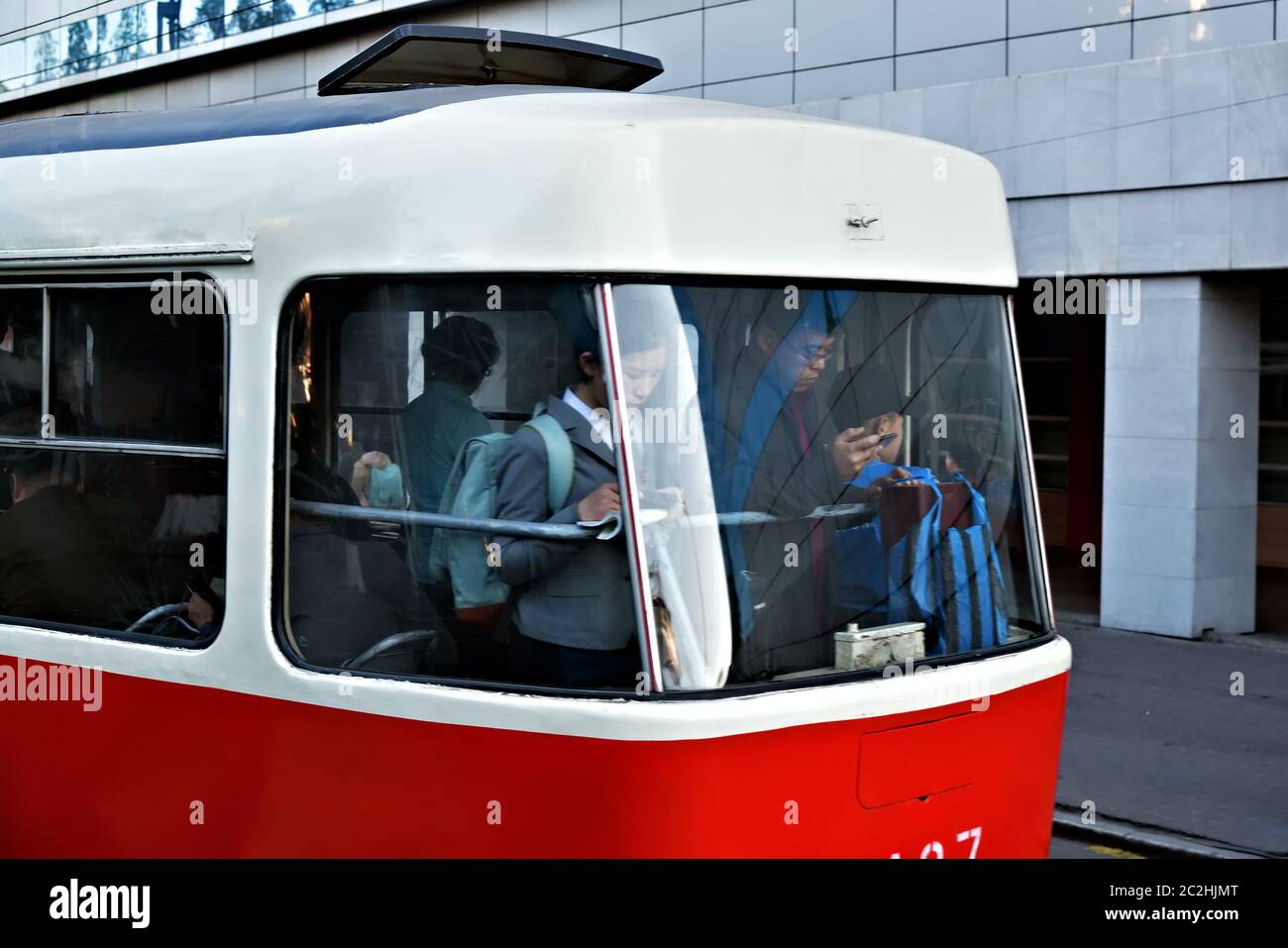 Pjöngjang, Nordkorea - 6. Mai 2019: Öffentlicher Verkehr in Pjöngjang. Passagiere fahren in einer Straßenbahn entlang einer Stadtstraße und schauen sich die heutigen Nachrichten auf Smartphones an Stockfoto