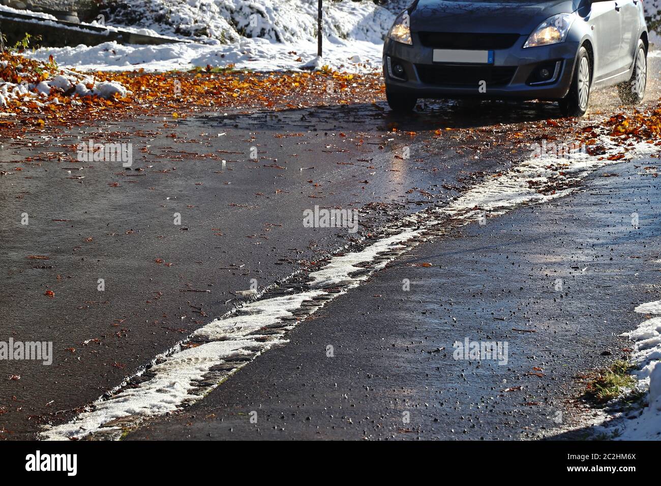 Unfallgefahr für Autos durch nasse Blätter und Schnee auf der Straße Stockfoto