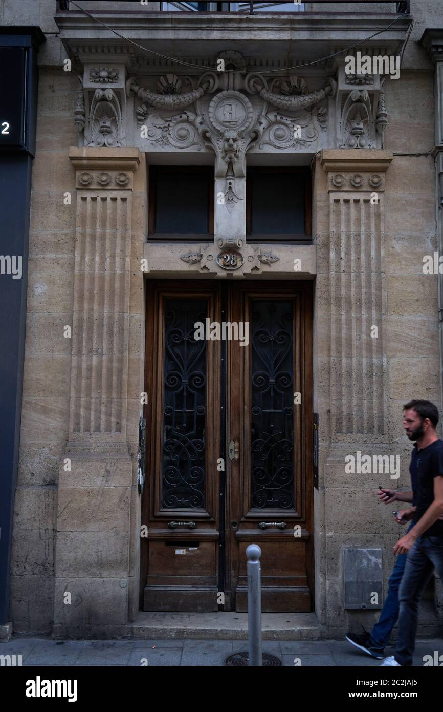 Ein Mann geht an einem kunstvoll geschnitzten Portal mit schmiedeeisernen Gittern vorbei, Hausnummer 28, in der Altstadt von Bordeaux, Frankreich Stockfoto
