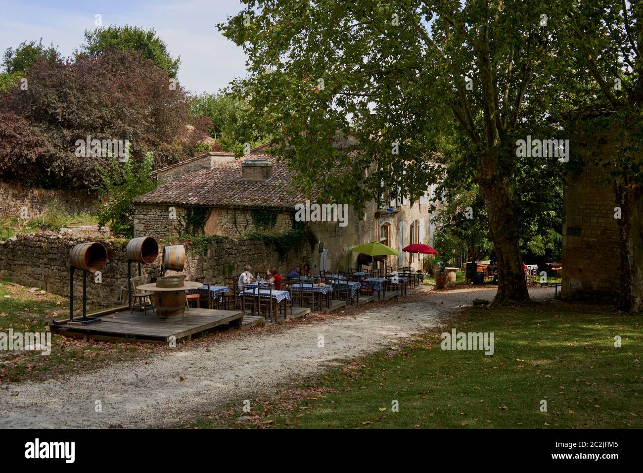 Schattige Café-Tische und eine antike Weinpresse im Dorf innerhalb der Zitadelle von Blaye, Gironde, Frankreich Stockfoto