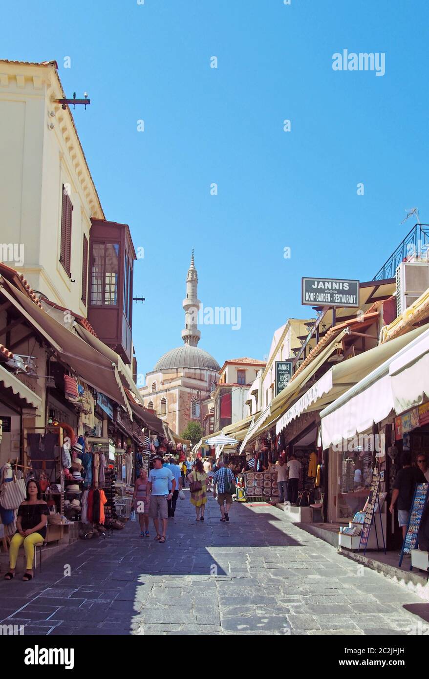 Touristen gehen eine Straße entlang, die mit Geschäften und Cafés in der Nähe der alten suleiman Moschee in rhodos Stadt gesäumt ist Stockfoto