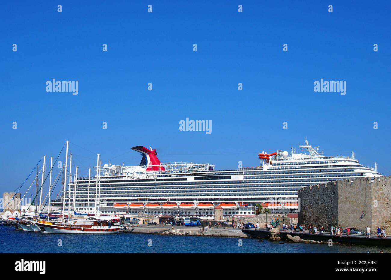 Touristen gehen entlang der Küste am Hafen von rhodos Stadt mit dem Kreuzfahrtschiff Karneval vista vertäut ne Stockfoto