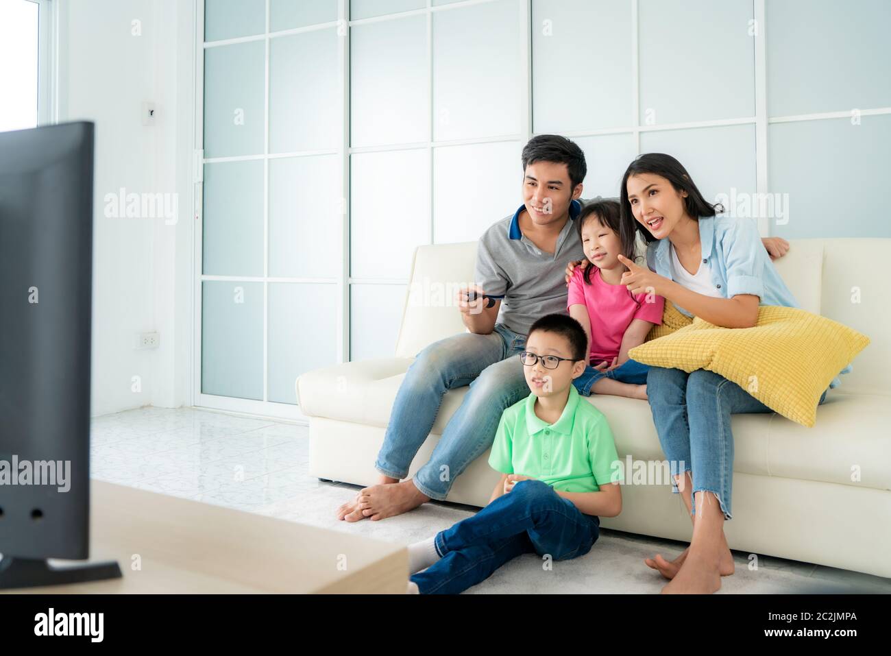 Asiatische glückliche Familie mit Vater, Mutter, Sohn und Tochter sitzen auf dem Sofa und Fernsehen zu Hause Konzept der Familie Werte, Urlaub Tag, holid Stockfoto