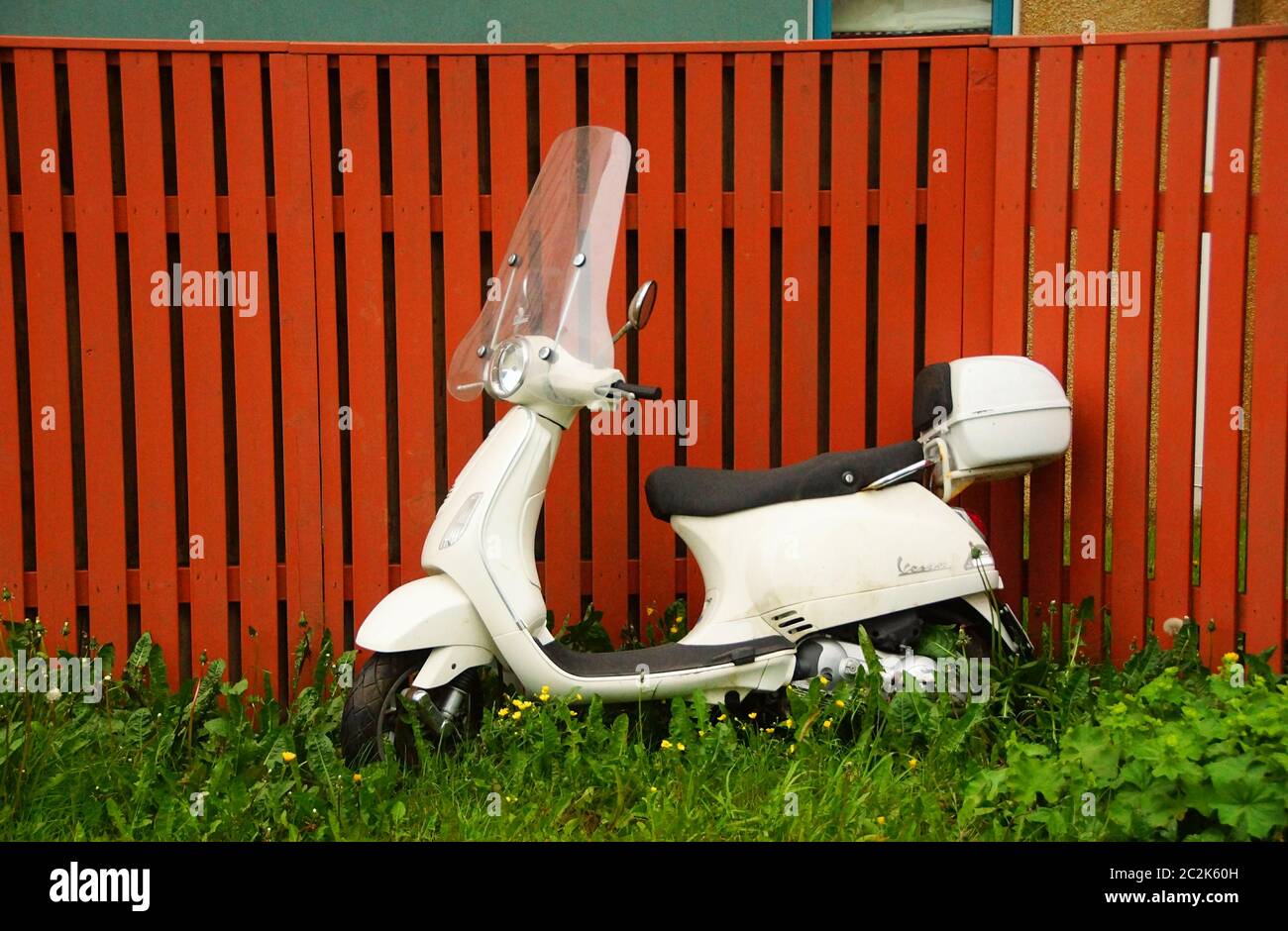 Eine weiße Vespa Motorroller an einem braunen Zaun Stockfoto