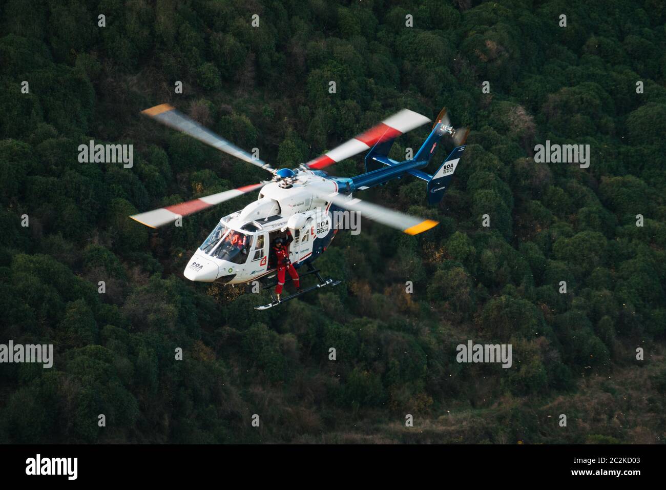 Ein Rettungshubschrauber MBB BK117 von Canterbury West Coast Air Rescue Trust senkt die Ausrüstung an den Standort eines Autos, das in Neuseeland an einem steilen Ufer herunterfiel Stockfoto