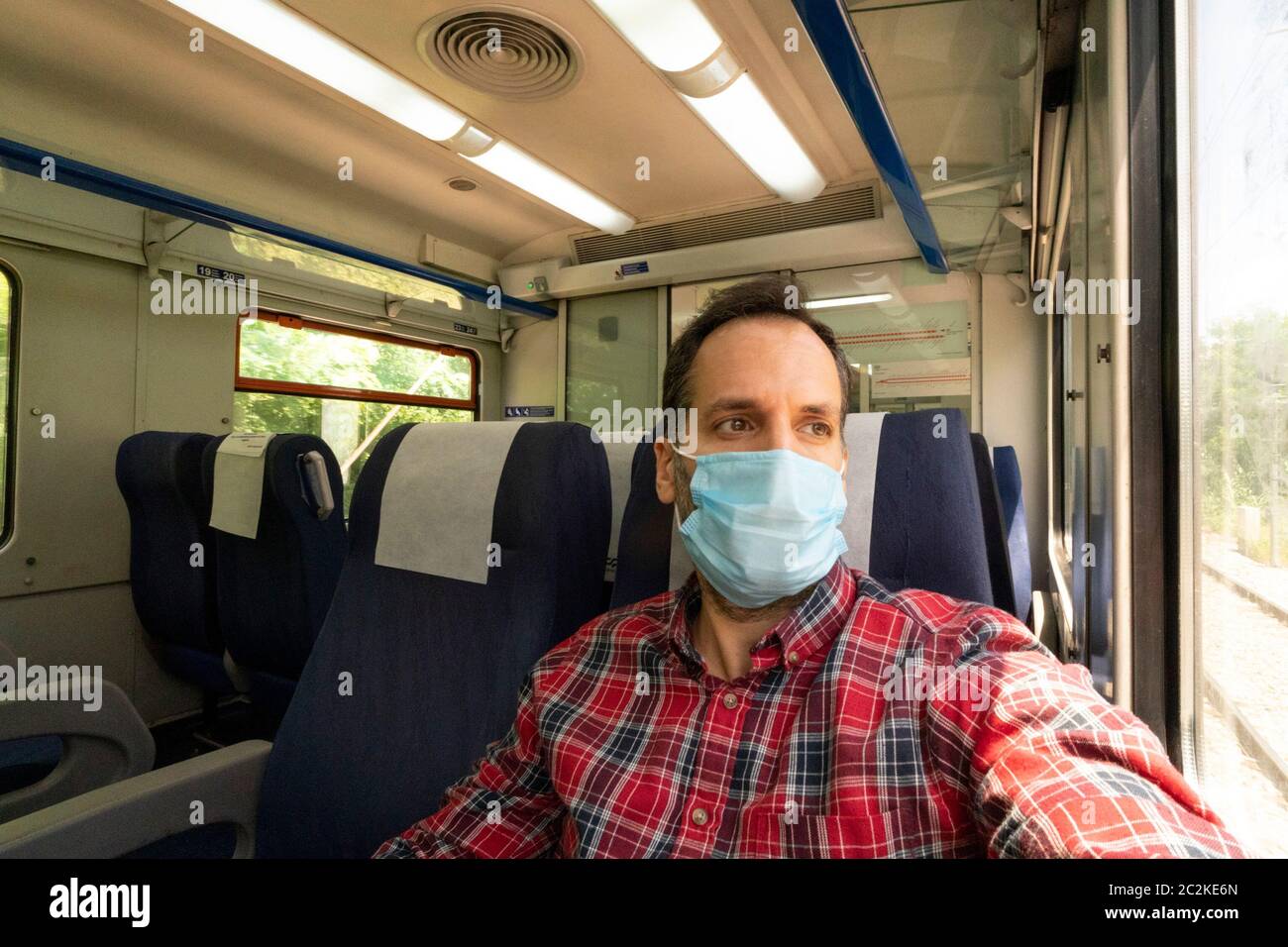 Mann in einem Zug mit Gesichtsmaske zum Schutz während der neuartigen Coronavirus COVID-19 Pandemie Stockfoto