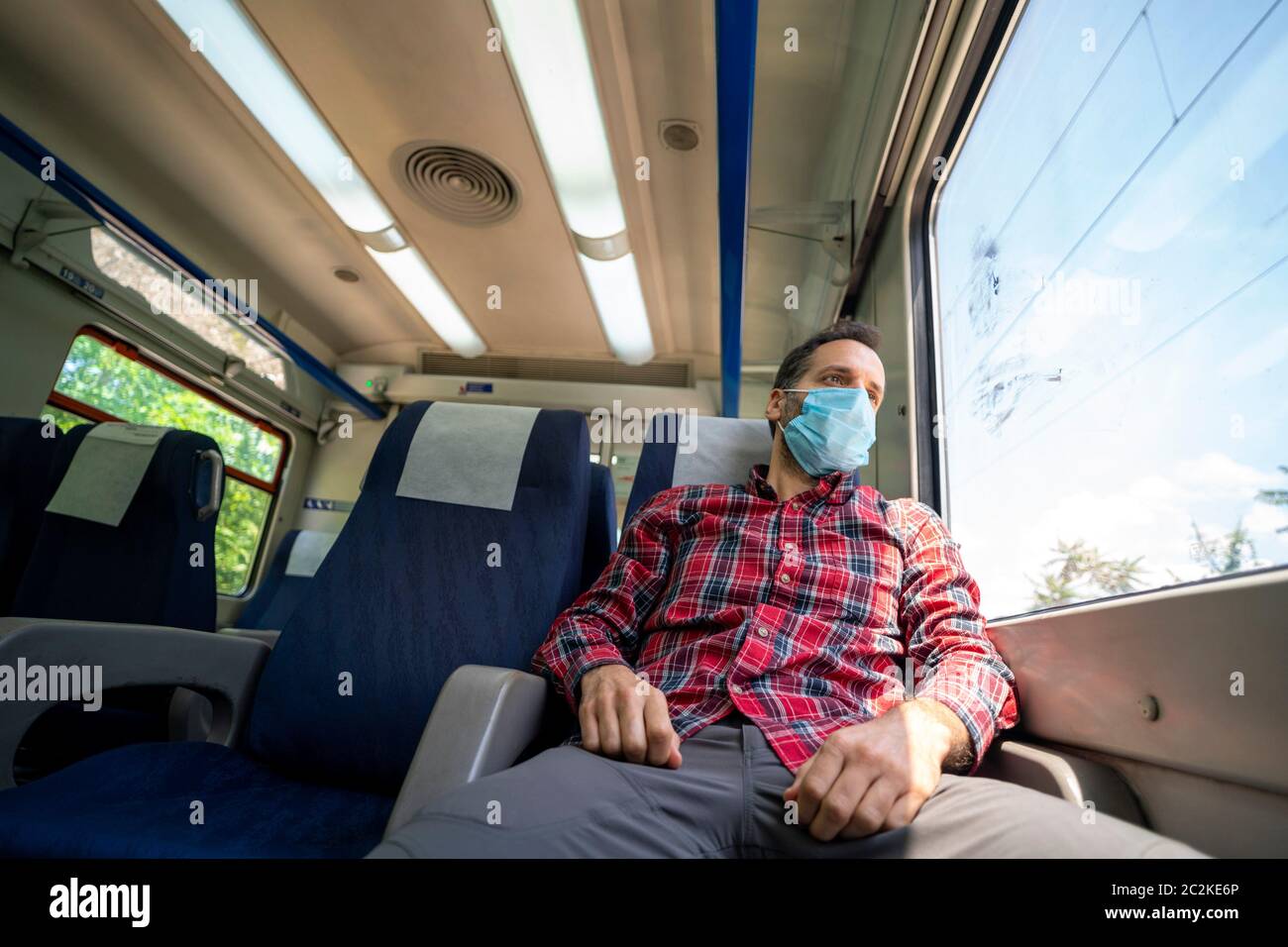 Mann in einem Zug mit Gesichtsmaske zum Schutz während der neuartigen Coronavirus COVID-19 Pandemie Stockfoto