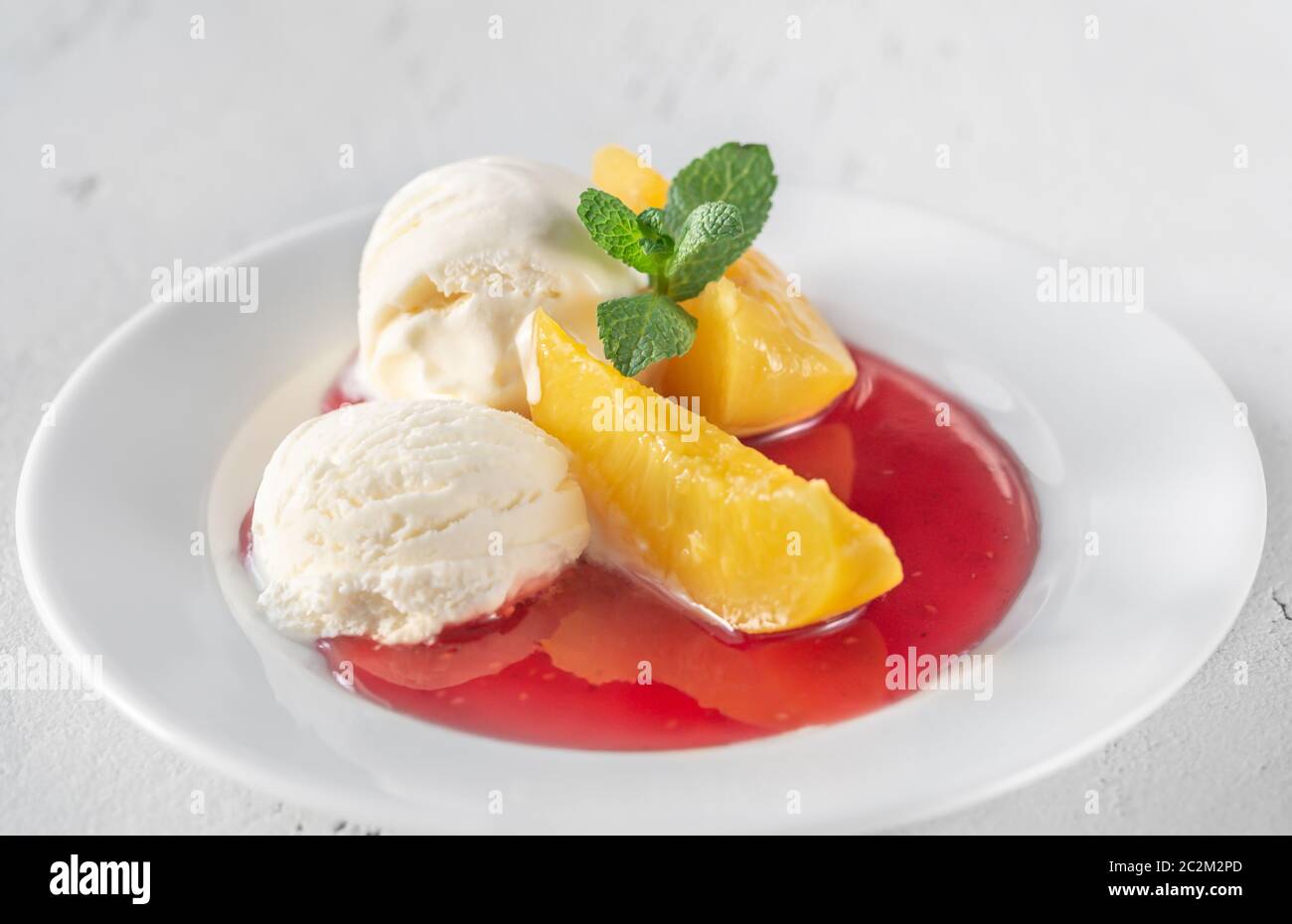 Pfirsich Melba - Dessert von Pfirsichen und Himbeersauce mit Vanilleeis Stockfoto