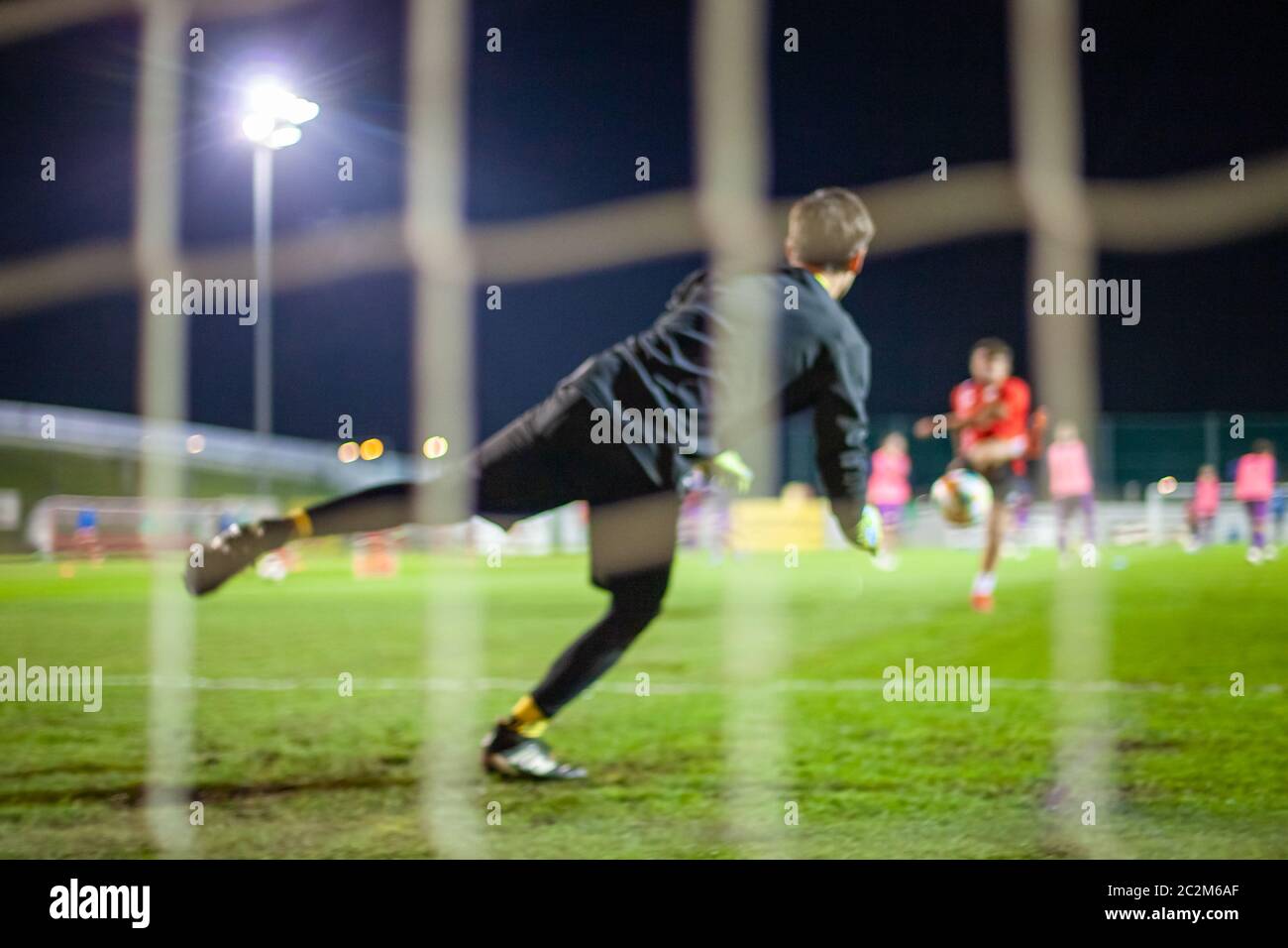 Torwart fangen den Ball wenn auf Ziel defensive während einer Nacht Fußballspiel Stockfoto