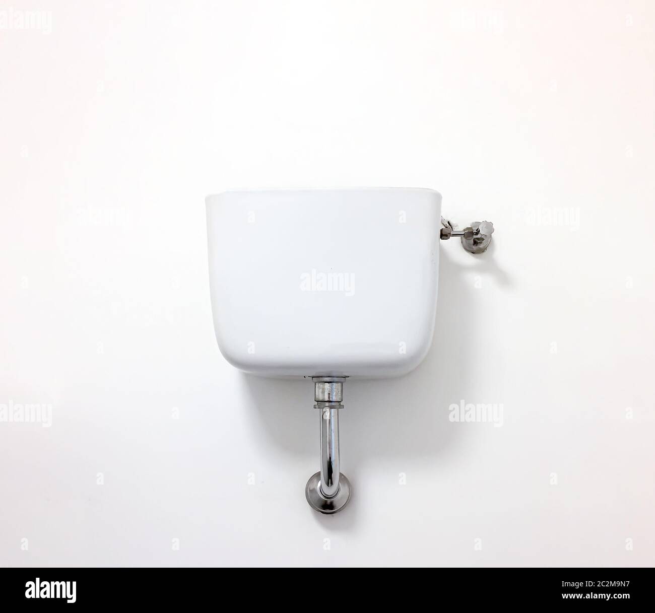 Toilettenspülung mit einer erhöhten Keramikzisterne mit Wasser mit einem Wasserhahn und einem Stahlabflussrohr. Reinigungs- und Hygienekonzept Stockfoto
