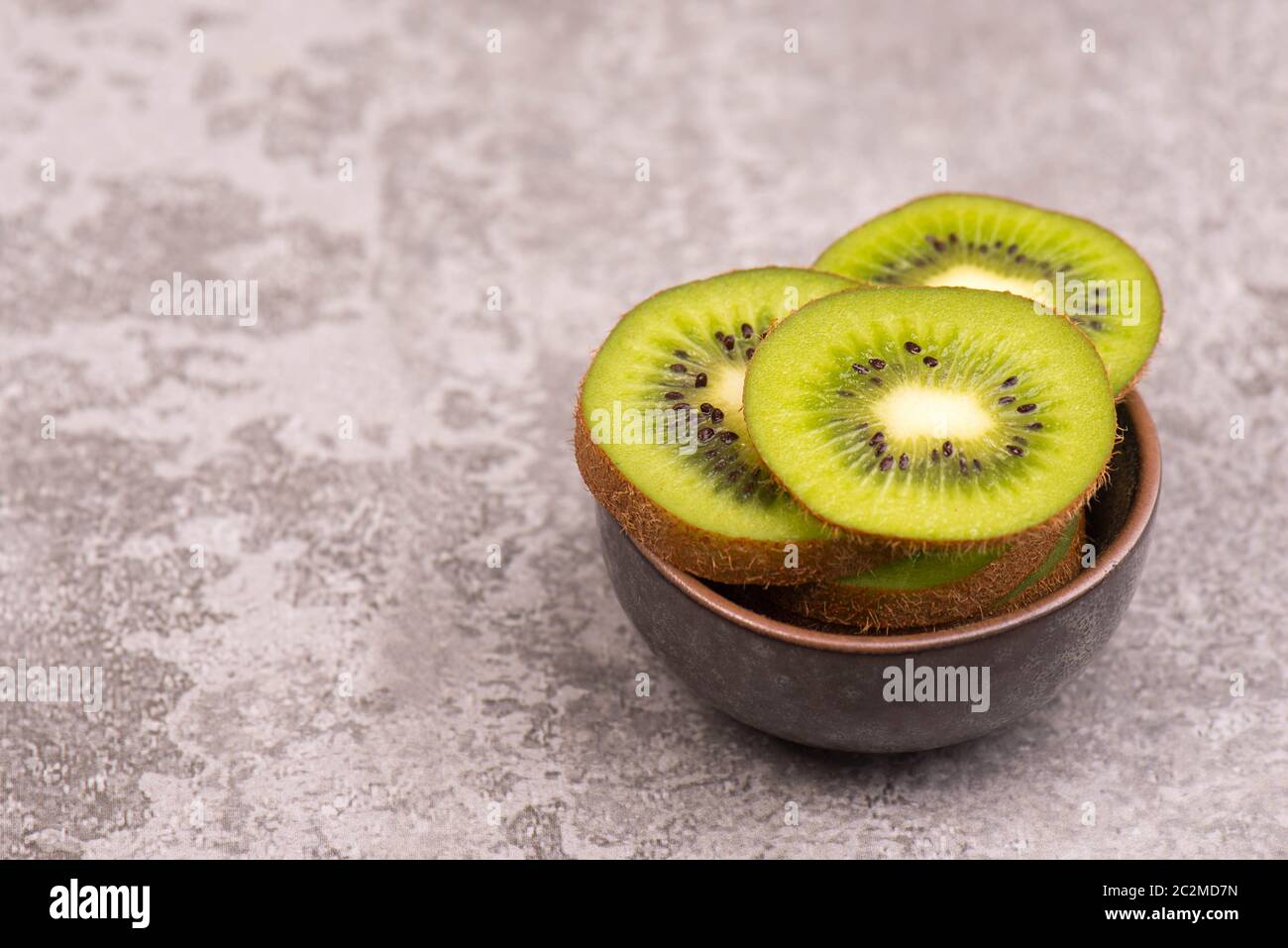 Kiwi-Scheiben auf einem grauen texturierten Hintergrund, leerer Kopierraum Stockfoto