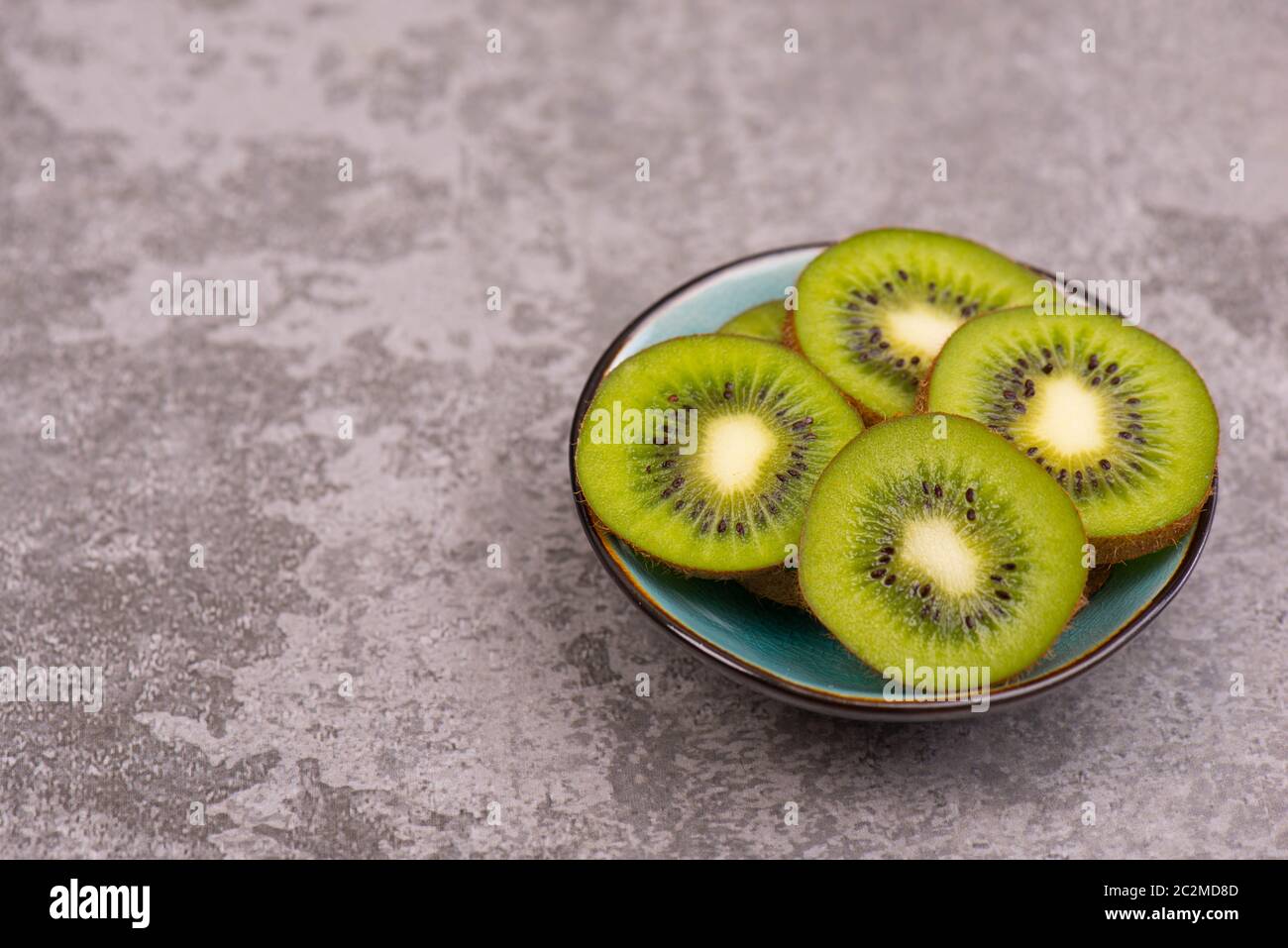 Kiwi-Scheiben auf einem grauen texturierten Hintergrund, leerer Kopierraum Stockfoto