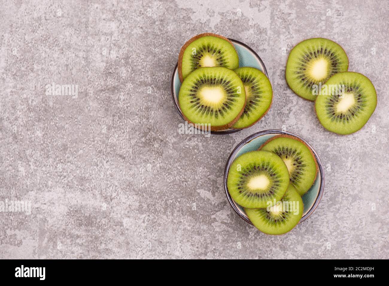 Kiwi-Scheiben auf einem grauen texturierten Hintergrund, leerer Kopierraum Stockfoto