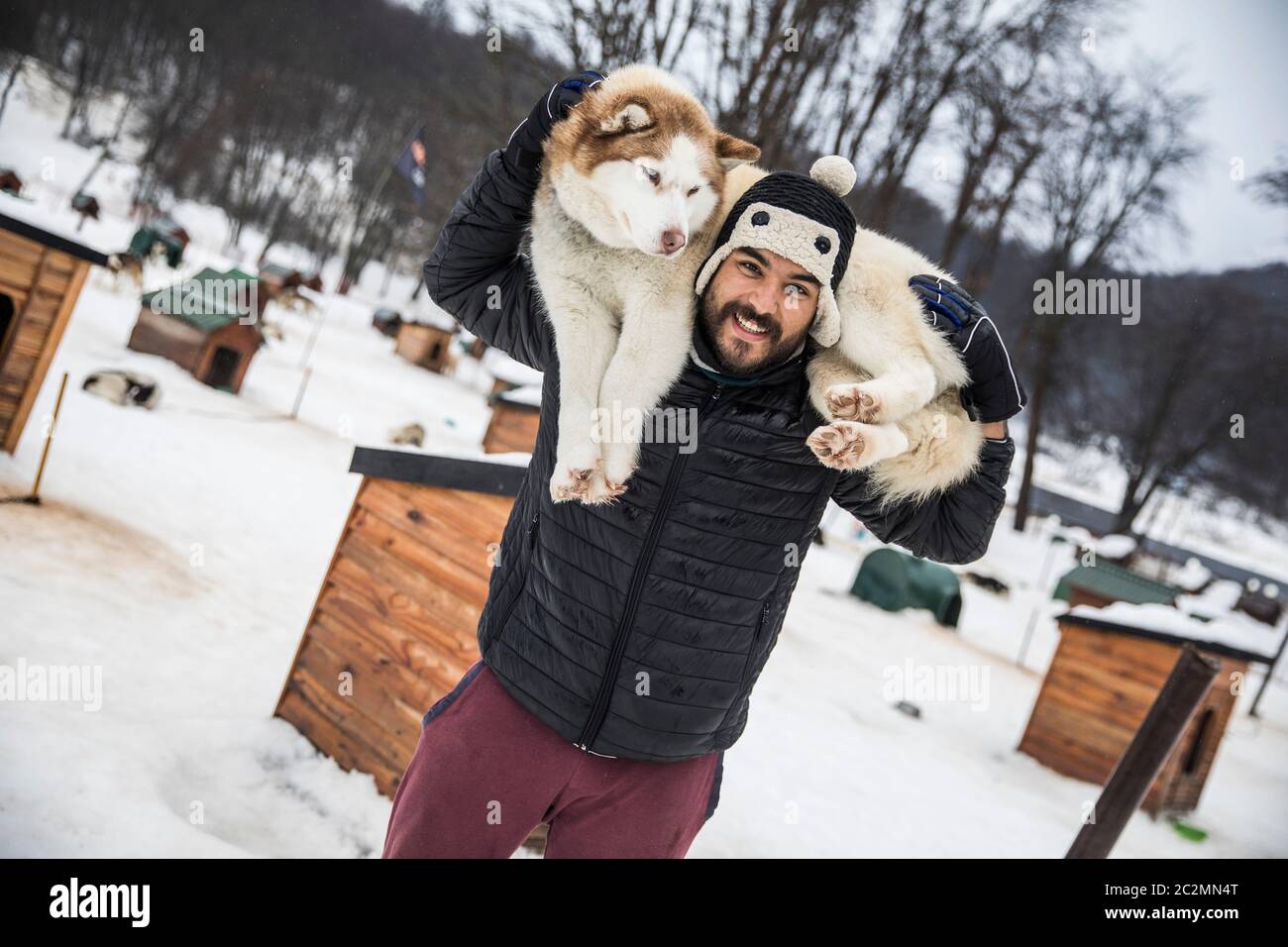 Brauner Mann, der einen Husky im Rücken trägt Stockfoto