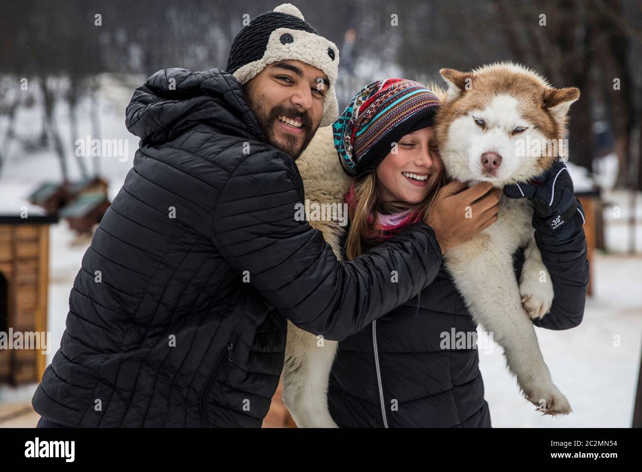 Paar mit einem sibirischen Hund im Winter von Schnee umgeben. Stockfoto