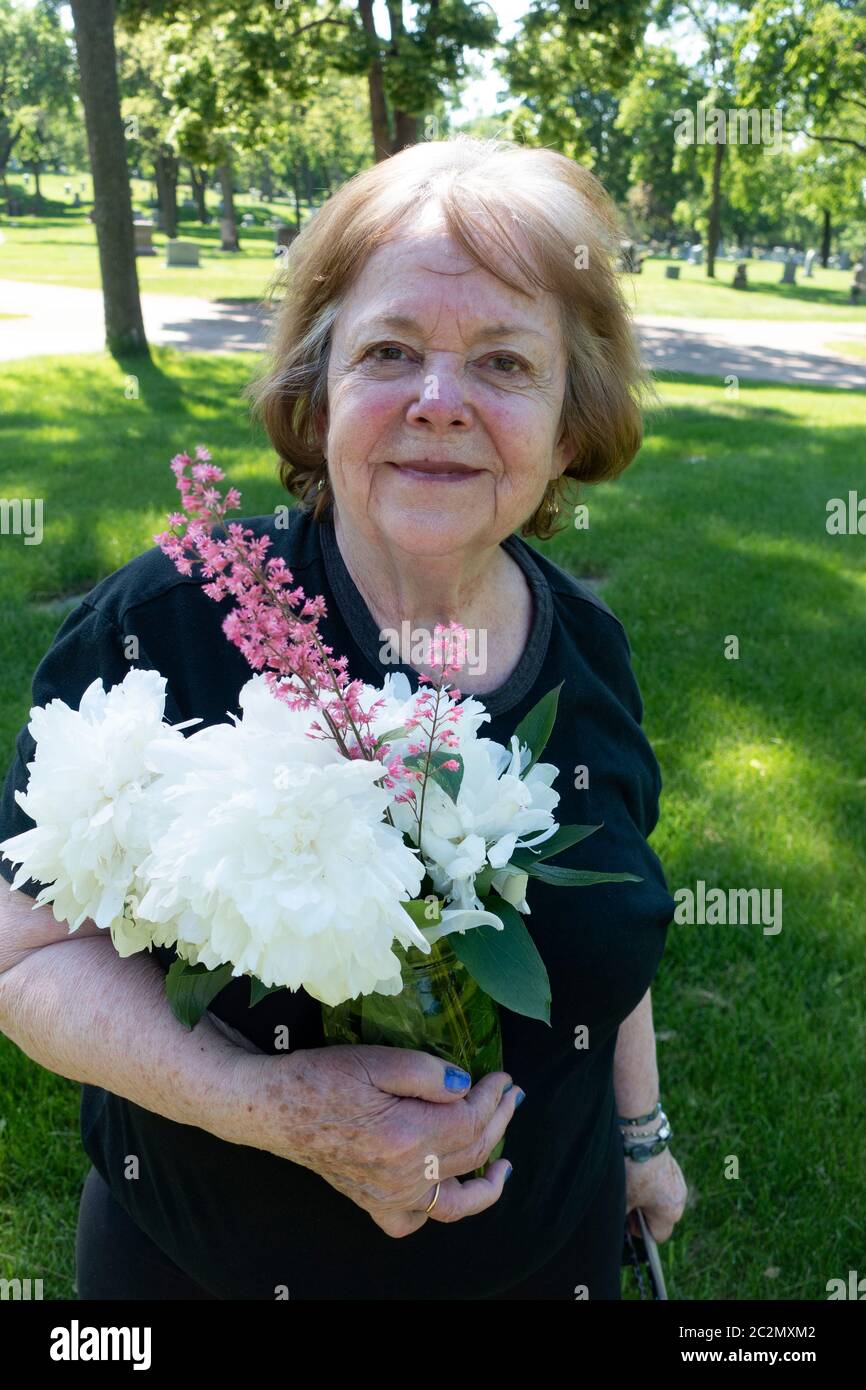 Fotografin und Künstlerin Mary Skjold hält einen Blumenstrauß, der in ihrem Garten bei der Grabstätte ihrer Eltern gepflückt wurde. Minneapolis Minnesota, USA Stockfoto